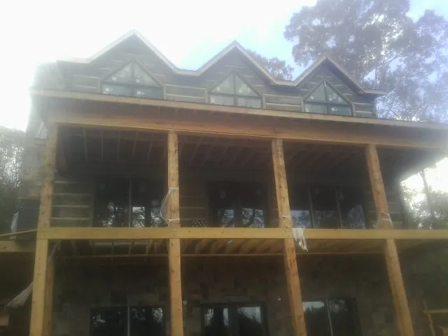 Dormers and porch framing on a large log home under construction — Roof Coating work by our crew in Midway Park