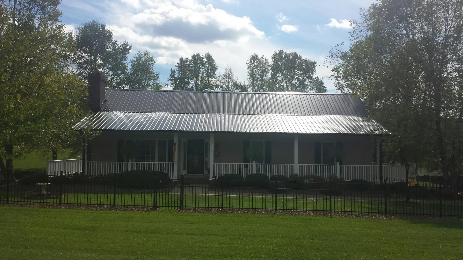 Gray metal roof on a brick ranch with a full width front porch — Gutter Guard Installation work by our crew in Midway Park