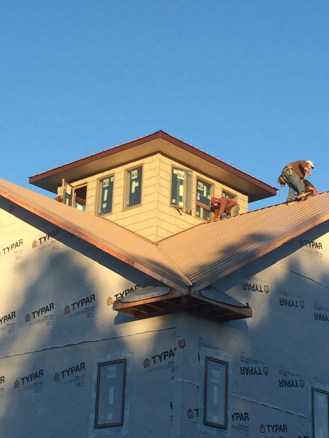 Roofers working around a rooftop cupola on a new metal roof at sunset — Roof Waterproofing in Midway Park by Roofing Brothers